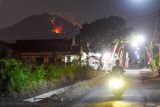 Warga melintas dengan latar belakang kebakaran hutan di Gunung Merapi Ungup-ungup di Bangsring, Wongsorejo, Banyuwangi, Jawa Timur, Selasa (20/8/2024). Menurut warga sekitar kebakaran diatas Gunung Merapi Ungup-ungup yang berada di kawasan Gunung Ijen itu terlihat sejak Senin (19/8) siang dan hingga saat ini kebakaran terus meluas karena sulitnya akses jalan untuk memadamkan. Antara Jatim/Budi Candra Setya/um