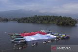 Foto udara petugas dan warga membetangkan bendera Merah Putih raksasa saat upacara bendera di Situ Lengkong, Desa Panjalu, Kabupaten Ciamis, Jawa Barat, Sabtu (17/8/2024). Upacara di atas permukaan danau dengan membentangkan bendera merah putih berukuran 750 meter persegi dan dikelilingi 2024 bendera itu untuk memperingati HUT Ke-79 Kemerdekaan RI. ANTARA FOTO/Adeng Bustomi/agr