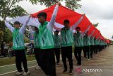 Sejumlah atlet Pontianak membentangkan bendera merah putih berukuran besar saat menyambut kedatangan Atlet panjat tebing Veddriq Leonardo peraih medali emas Olimpiade Paris 2024 di Pontianak, Kalimantan Barat, Rabu (21/8/2024). Pemerintah Provinsi Kalimantan Barat menyambut kedatangan atlet panjat tebing asal Kota Pontianak itu dengan mengadakan arak-arakan keliling kota sebagai ungkapan kebanggaan terhadap Veddriq Leonardo yang telah mengharumkan nama Indonesia. ANTARA FOTO/Jessica Wuysang