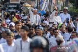 Pasangan bakal calon Gubernur dan Wakil Gubernur Jawa Barat Dedi Mulyadi (kiri) dan Erwan Setiawan (kanan) menyapa warga dan pendukung saat berjalan untuk pendaftaran di Kantor KPU Jawa Barat, Bandung, Selasa (27/8/2024). Pasangan Dedi Mulyadi dan Erwan Setiawan mendaftarkan diri sebagai peserta Pilgub Jawa Barat 2024 dengan dukungan Partai Gerindra, Partai Golkar, PAN, Partai Demokrat, dan PSI serta sembilan partai lain non parlemen. ANTARA FOTO/Novrian Arbi/agr