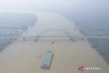 Foto udara kapal tongkang melintasi Jembatan Muara Sabak yang diselimuti kabut asap akibat kebakaran hutan dan lahan (karhutla) di Tanjung Jabung Timur, Jambi, Selasa (27/8/2024). Sebagian wilayah di kabupaten itu mulai terdampak kabut asap akibat karhutla yang terjadi di daerah itu sejak tiga hari terakhir yang mengakibatkan terbatasnya jarak pandang dan buruknya kualitas udara sehingga mengganggu kesehatan. ANTARA FOTO/Wahdi Septiawan/aww.