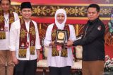 Ketua KPU Jatim Aang Kunaifi (kanan) memberikan cinderamata kepada bakal calon Gubernur dan Wakil Gubernur Jawa Timur Khofifah Indar Parawansa (tengah) dan Emil Elestianto Dardak (kedua kiri) saat pendaftaran di Kantor KPU Provinsi Jawa Timur, Surabaya, Jawa Timur, Rabu (28/8/2024). Khofifah Indar Parawansa dan Emil Elestianto Dardak resmi mendaftarkan diri sebagai peserta Pilgub Jatim 2024 dengan dukungan 15 partai yakni Gerindra, Golkar, Demokrat, NasDem,  Perindo, PAN, PKS, PPP, PSI, PKN, PBB, Partai Gelora, Partai Buruh, Partai Garuda, dan Partai Prima. Antara Jatim/Rizal Hanafi/um 