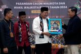 Ketua KPU Kota Blitar Rangga Bisma Aditya (kanan) didampingi Ketua Bawaslu Kota Blitar Roma Hudi Arif (kiri) menyerahkan cinderamata boneka maskot pilkada kota blitar 2024 