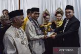 Ketua KPU Kota Tasikmalaya Asep Riswmawan (kanan) memberikan cendramata kepada bakal calon wali kota Tasikmalaya dan balon wakil wali kota Tasikmalaya M Yusuf (kedua kiri) - Hendro Nugraha (kiri) saat pendaftaran Pilkada 2024 di KPU Kota Tasikmalaya, Jawa Barat, Rabu (28/8/2024). Pasangan M Yusuf dan Hendro Nugraha mendaftarkan diri sebagai bakal calon walikota Tasikmalaya yang diusung oleh partai Golkar dan PAN. ANTARA FOTO/Adeng Bustomi/agr