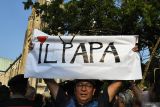 Seorang warga membentangkan poster saat menanti kedatangan Paus Fransiskus di depan Gereja Katedral, Jakarta,Rabu (4/9/2024). Dalam kunjungannya, pemimpin Takhta Suci Vatikan tersebut akan berdialog dengan uskup, imam, diakon, pelaku hidup bakti, seminaris, dan katekis. ANTARA FOTO/Fakhri Hermansyah/wsj.