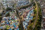 Foto udara sejumlah kendaraan melintas di sekitar Kampung Warna-warni Jodipan, Malang, Jawa Timur, Rabu (4/9/2024). Jumlah desa mandiri di Jawa Timur meningkat 43,54 persen dari tahun sebelumnya yakni dari 2.800 desa di tahun 2023 menjadi 4.019 desa di tahun 2024 dan menjadi yang tertinggi di Indonesia. Antara Jatim/Muhammad Mada/um