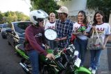 Divisi Sosialisasi, Pendidikan Pemilih dan Partisipasi Masyarakat Komisi Pemilihan Umum (KPU) Provinsi Jawa Timur Nur Salam (ketiga dari kanan) memberikan cinderamata kepada pengendara motor saat sosialisasi di Surabaya, Jawa Timur, Jumat (6/9/2024). KPU Provinsi Jawa Timur melakukan sosialisasi di jalanan itu untuk mengajak masyarakat menggunakan hak pilihnya pada Pilgub Jawa Timur 2024 yang digelar 27 November 2024. Antara Jatim/Didik Suhartono/um