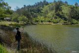 Seorang wisatawan mengabadikan gambar saat mengunjungi objek wisata Ranu Regulo di Lumajang, Jawa Timur, Kamis (12/9/2024). Balai Besar Taman Nasional Bromo Tengger Semeru (BB TNBTS) membuka kembali kawasan Ranu Regulo pada Selasa (10/9) setelah sempat ditutup sejak 5 Februari 2024 dengan batasan kuota berkemah maksimal 300 orang perhari.  ANTARA Jatim/Irfan Sumanjaya/mas.