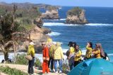 Sejumlah pengunjung menikmati pemandangan alam di Pantai Pudak, Kabupaten Blitar, Jawa Timur, Minggu (15/9/2024). Wisata yang baru dibuka pada awal tahun 2024 seiring dibangunnya Jalan Lintas Selatan Jawa tersebut ramai pengunjung pada libur panjang akhir pekan yang bertepatan dengan libur peringatan Maulid Nabi Muhammad SAW. ANTARA Jatim/Prasetia Fauzani/mas.