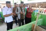 Pimpinan Badan Amil Zakat Nasional (BAZNAS) Pembina Wilayah Provinsi Jawa Timur Nur Chamdani (tengah), didampingi Asisten Administrasi Umum Pemkab Jember Harry Agustriyono (kiri) menyimak pemaparan proses pembuatan kompos usai meluncurkan program Balai Ternak BAZNAS dan Rumah Kompos di Desa Jambearum, Sumberjambe, Jember, Jawa Timur, Rabu (18/9/024). Balai Ternak merupakan salah satu program BAZNAS dalam rangka pengentasan kemiskinan di wilayah pedesaan yang menyasar peternak mustahik sebagai penerima manfaat, dengan komoditas ternak yang dibudidayakan, yaitu domba, kambing, sapi dan ayam broiler. Antara Jatim/Seno/um