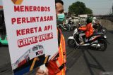 Komunitas pecinta kereta api membentangkan poster saat sosialisasi keselamatan di perlintasan kereta api di Jalan Dupak Rukun, Surabaya, Jawa Timur, Kamis (19/9/2024). Sosialisasi bertema Taat Berlalu Lintas di Perlintasan, Cermin Budaya Bangsa Indonesia Maju itu bertujuan meningkatkan kesadaran masyarakat pentingnya mentaati peraturan lalu lintas saat melintas di perlintasan sebidang kereta api demi keselamatan. Antara Jatim/Didik Suhartono/um