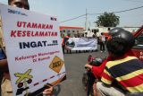 Petugas dan Komunitas pecinta kereta api membentangkan poster saat sosialisasi keselamatan di perlintasan kereta api di Jalan Dupak Rukun, Surabaya, Jawa Timur, Kamis (19/9/2024). Sosialisasi bertema Taat Berlalu Lintas di Perlintasan, Cermin Budaya Bangsa Indonesia Maju itu bertujuan meningkatkan kesadaran masyarakat pentingnya mentaati peraturan lalu lintas saat melintas di perlintasan sebidang kereta api demi keselamatan. Antara Jatim/Didik Suhartono/um