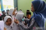 Guru memakaikan masker kepada siswa saat pembagian masker di SD Negeri 1 Lebak Gebang, Kota Cilegon, Banten, Jumat (20/9/2024). Dinkes Kota Cilegon membagikan 1.000 masker kepada masyarakat yang tinggal dekat dengan TPSA Bagendung untuk mencegah terjangkitnya penyakit Infeksi Saluran Pernapasan Akut (ISPA) akibat asap kebakaran sampah yang masih terjadi hingga saat ini. ANTARA FOTO/Muhammad Bagus Khoirunas/gp