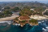 Foto udara Tanjung Penyu terlihat dari pantai Ungapan di sekitar Jalur Lintas Selatan Gedangan, Malang, Jawa Timur, Minggu (22/9/2024). Keberadaan Jalur Lingkar Selatan (JLS) sejauh 50 kilometer di pesisir Malang yang sudah ada sejak tahun 2016 itu kini membawa dampak positif bagi perkembangan sektor pariwasata di kawasan tersebut diantaranya telah resmi dibuka sekitar 33 pantai yang dikelola oleh kelompok masyarakat setempat bersama Perhutani sehingga dapat menunjang perekonomian di wilayah tersebut.. ANTARA Jatim/Muhammad Mada/mas.