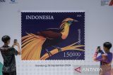 Dua anak memotret contoh desain perangko Non-Fungible Token (NFT) Indonesia seri art mural cenderawasih usai peluncuran di Kantor Pusat PT Pos Indonesia, Bandung, Jawa Barat, Jumat (27/9/2024). PT Pos Indonesia resmi meluncurkan edisi perangko NFT pertama di Indonesia sebagai alat pembayaran yang sah dalam pengiriman barang sekaligus untuk koleksi digital filateli di platform teknologi berbasis Blockchain dalam langkah awal memasuki ekonomi digital. ANTARA FOTO/Novrian Arbi/agr