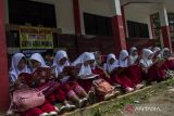 Siswa membaca buku di depan ruang kelas yang disegel di SDN Senangsari, Kecamatan Pagelaran, Pandeglang, Banten, Kamis (3/10/2024). Menurut penuturan pihak sekolah ruang kelas baru (RKB) yang diperuntukkan bagi siswa kelas enam tersebut telah disegel oleh pihak yang mengaku ahli waris, sehingga kegiatan belajar mengajar terpaksa dilakukan di teras kelas atau dipindahkan ke ruang kelas lain yang tersedia. ANTARA FOTO/Angga Budhiyanto/gp