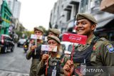 Petugas Satpol PP menunjukan topeng tersenyum yang dibagikan peserta aksi yang melakukan aksi di Jalan Braga, Bandung, Jawa Barat, Jumat (4/10/2024). Pegawai Kantor LKBN Antara Biro Jawa Barat bersama mahasiswa Unpad, Upi, dan UIN Sunan Gunung Djati menggelar aksi membagikan topeng tersenyum yang dilaksanakan dalam rangka memperingati Hari Senyum Sedunia. ANTARA FOTO/Raisan Al Farisi/agr