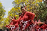 Sejumlah peserta menari Sanduk berlatar belakang bunga Tabebuya saat mengikuti lomba tari Sanduk di Jalan Ksatrian Pusdik Arhanud, Batu, Jawa Timur, Sabtu (5/10/2024). Agenda yang diikuti ratusan peserta itu diinisiasi pemerintah setempat bersama Pusat Pendidikan Artileri Pertahanan Udara (Pusdik Arhanud) sebagai upaya mempromosikan pariwisata Kota Batu dan memeriahkan perayaan Hari Ulang Tahun (HUT) ke-79 TNI. Antara Jatim/Muhammad Mada/um 