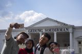 Warga berfoto dengan latar belakang bangunan cagar budaya Gedung Soedirman di Kota Cimahi, Jawa Barat, Minggu (6/10/2024). Pemerintah Daerah Kota Cimahi menginisiasi program Cimahi Military Heritage Tourism yang bertujuan untuk mendorong pariwisata Kota Cimahi melalui konsep eduwisata pengenalan sejarah militer dan bangunan-bangunan bersejarah. ANTARA FOTO/Abdan Syakura/agr