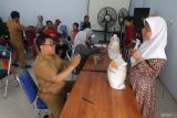 Petugas mendokumentasikan warga penerima manfaat saat pengambilan bantuan pangan cadangan beras pemerintah di Balai Kelurahan Pojok, Kota Kediri, Jawa Timur, Selasa (8/10/2024). Pemerintah daerah setempat bersinergi dengan Perum Bulog menyalurkan bantuan 336.320 kilogram beras periode bulan Oktober 2024 untuk 33.632 keluarga penerima manfaat. ANTARA Jatim/Prasetia Fauzani/mas.