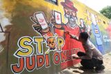 Kapolsek Plemahan AKP Bowo Wicaksono menyelesaikan pembuatan mural bertema cegah judi online pada dinding di Kediri, Jawa Timur, Rabu (9/10/2024). Polisi yang memiliki hobi melukis tersebut memanfaatkan media tembok Polsek dan Kantor Kecamatan daerah setempat untuk dibuat mural sebagai upaya edukasi sekaligus mendukung pemerintah mencegah judi online kepada masyarakat. ANTARA Jatim/Prasetia Fauzani/mas.