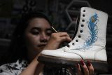 Mahasiswa generasi Z Helena Alfionitasari Suryawijaya merapikan warna cat pada sepatu lukis karyanya sebelum dikirim ke konsumen di rumah produksi Utapes Paint, Malang, Jawa Timur, Senin (14/10/2024). Pelukis muda tersebut mendirikan usaha sepatu lukis dengan produksi rata-rata per minggu 5 pasang untuk kemudian diekspor ke Belanda serta dijual ke berbagai kota di Indonesia melalui pasar digital dengan harga Rp100 ribu hingga Rp2,5 juta per pasang tergantung kerumitan lukisannya. ANTARA Jatim/Ari Bowo Sucipto/mas.