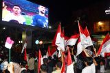 Sejumlah warga mengangkat Bendera Merah Putih saat menyaksikan Timnas Indonesia melawan Timnas China pada pertandingan keempat putaran ketiga kualifikasi Piala Dunia 2026 zona Asia melalui videotron di kawasan Alun-alun Kota Madiun, Jawa Timur, Selasa (15/10/2024). Pemkot Madiun menyediakan fasilitas videotron untuk menyaksikan pertandingan tersebut bagi warganya bersama pejabat daerah. Antara Jatim/Siswowidodo/um 