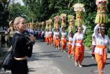 Wisatawan mancanegara menyaksikan umat Hindu menjunjung Gebogan atau sesajen berisi kue, buah, bunga dan hiasan janur saat tradisi Mapeed di objek wisata Alas Kedaton, Desa Kukuh, Tabanan, Bali, Rabu (16/10/2024). Tradisi yang digelar pada 16-18 Oktober 2024 tersebut diikuti ratusan perempuan Bali dalam rangkaian upacara persembahyangan di Pura Dalem Kahyangan Kedaton sekaligus untuk meningkatkan kunjungan wisatawan ke objek wisata itu. ANTARA FOTO/Nyoman Hendra Wibowo/wsj.