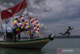 Seorang anak melompat dari atas perahu yang bersandar di Pulau Liwungan, Kabupaten Pandeglang, Banten, Minggu (20/10/2024). Objek wisata yang biasa ramai dikunjungi pada hari libur tersebut dapat ditempuh menggunakan perahu yang disewakan dengan kisaran harga Rp500 ribu hingga Rp1 juta untuk satu rombongan melalui Dermaga Cipanon atau Kampung Lelang Baru, Kecamatan Panimbang. ANTARA FOTO/Angga Budhiyanto/gp