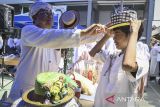 Founder Yayasan Topi Bambu, Agus Hasanudin (kiri) memakaikan topi bambu kepada seorang siswa di SMAN 15 Kabupaten Tangerang, Banten, Selasa (22/10/2024). Yayasan Topi Bambu memberikan pengenalan dan pelatihan membuat kerajinan bambu seperti topi dan peci sebagai upaya melestarikan warisan budaya khas Kabupaten Tangerang sejak tahun 1887 tersebut kepada generasi muda. ANTARA FOTO/Sulthony Hasanuddin/gp