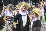 Sejumlah siswa berswafoto saat mencoba topi bambu di SMAN 15 Kabupaten Tangerang, Banten, Selasa (22/10/2024). Yayasan Topi Bambu memberikan pengenalan dan pelatihan membuat kerajinan bambu seperti topi dan peci sebagai upaya melestarikan warisan budaya khas Kabupaten Tangerang sejak tahun 1887 tersebut kepada generasi muda. ANTARA FOTO/Sulthony Hasanuddin/gp