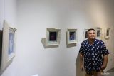 Alam Taslim berfoto dengan karyanya saat pembukaan pameran seni visual Alam Bawah Sadar Dalam Tiga Babak di n0lkecil Creative Space, Surabaya, Jawa Timur, Jumat (25/10/2024). Pameran kolektif tiga seniman yaitu Alam Taslim, Gandez Sholihah dan Marian Kevin yang berlangsung hingga 10 November tersebut mengusung konsep bercerita tentang kehidupan dalam 22 karya visual yang dikreasikan dengan memadukan ilustrasi digital dan teknik cetak manual sinar UV cyanotype di media kaca. ANTARA Jatim/Moch Asim.