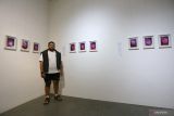 Marian Kevin berfoto dengan karyanya saat pembukaan pameran seni visual Alam Bawah Sadar Dalam Tiga Babak di n0lkecil Creative Space, Surabaya, Jawa Timur, Jumat (25/10/2024). Pameran kolektif tiga seniman yaitu Alam Taslim, Gandez Sholihah dan Marian Kevin yang berlangsung hingga 10 November tersebut mengusung konsep bercerita tentang kehidupan dalam 22 karya visual yang dikreasikan dengan memadukan ilustrasi digital dan teknik cetak manual sinar UV cyanotype di media kaca. ANTARA Jatim/Moch Asim.