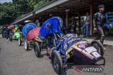 Mahasiswa berjalan di dekat deretan mobil listrik saat Kompetisi Mobil Listrik Indonesia 2024 kategori slalom di kampus Politeknik Negeri Bandung, Kabupaten Bandung Barat, Jawa Barat, Selasa (29/10/2024).Kompetisi yang diikuti 24 tim dari 21 Perguruan Tinggi di Indonesia tersebut sebagai upaya untuk meningkatkan kreativitas mahasiswa serta menambah kesadaran dalam menanggapi isu global tentang lingkungan hidup dan energi dengan cara menciptakan teknologi yang ramah lingkungan dan mengurangi pemakaian bahan bakar minyak. ANTARA FOTO/Abdan Syakura/agr