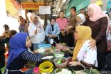 Calon Gubernur Jawa Timur nomor urut 2 Khofifah Indar Parawansa (kanan) menyapa penjual bubur khas Madura saat berkunjung ke Pasar Atom, Surabaya, Jawa Timur, Senin (4/11/2024). Kunjungan tersebut dalam rangka mendekatkan sekaligus meminta dukungan atas pencalonannya sebagai calon Gubernur Jawa Timur kepada para pedagang, pengunjung serta pegawai toko di pasar itu. ANTARA Jatim/Moch Asim.