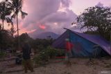 Sejumlah warga melihat ke arah Gunung Lewotobi Laki-laki yang erupsi di lokasi pengungsian swadaya di bukit di utara Desa Pululera, Wulanggitang, Kabupaten Flores Timur, Nusa Tenggara Timur, Sabtu (9/11/2024). Sekitar 700 warga Desa Pululera mengungsi secara swadaya ke sebuah bukit yang berjarak 10 kilometer dari pusat erupsi Lewotobi agar mereka lebih mudah dalam mengawasi rumah, hewan ternak dan perkebunan mereka. ANTARA FOTO/Aditya Pradana Putra/wsj.