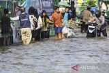 Sejumlah warga menerjang banjir di Jalan Ceger Raya, Jurangmangu Barat, Pondok Aren, Tangerang Selatan, Banten, Selasa (12/11/2024). Sebanyak 500 kepala keluarga terdampak banjir dan melumpuhkan akses Jalan Ceger Raya sejak Senin sore (11/11/2024) yang disebabkan proyek tanggul kali jebol tidak kuat menahan debit air hujan. ANTARA FOTO/Sulthony Hasanuddin/gp