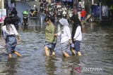 Sejumlah pelajar menerjang banjir di Jalan Ceger Raya, Jurangmangu Barat, Pondok Aren, Tangerang Selatan, Banten, Selasa (12/11/2024). Sebanyak 500 kepala keluarga terdampak banjir dan melumpuhkan akses Jalan Ceger Raya sejak Senin sore (11/11/2024) yang disebabkan proyek tanggul kali jebol tidak kuat menahan debit air hujan. ANTARA FOTO/Sulthony Hasanuddin/gp