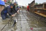 Sejumlah pekerja membuat penahan tanggul kali yang jebol saat banjir merendam Perumahan Taman Mangu Indah, Jurangmangu Barat, Pondok Aren, Tangerang Selatan, Banten, Selasa (12/11/2024). Pekerja membuat penahan tanggul kali sementara sepanjang 20 meter menggunakan papan, karung berisi pasir, dan rangka besi cor untuk mengurangi debit air yang masuk ke pemumikan warga. ANTARA FOTO/Sulthony Hasanuddin/gp