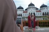 Seorang warga membantu memotretkan wisatawan Kapal Pesiar saat mengunjungi objek wisata sejarah Masjid Raya Baiturrahman, Banda Aceh, Aceh, Senin (11/11/2024). Kapal Pesiar M V Le Jaques Cartier berbedera Perancis yang membawa sebanyak 150 wistawan  itu mengunjungi sejumlah objek wisata di Aceh sebelum melanjutkan perjalan ke Singapura . ANTARA FOTO/Ampelsa.