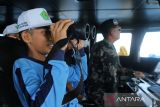 Seorang pelajar menggunakan teropong duduk bersama kapten  Kapal Pengawas HIU 12  saat kegiatan Joy Sailing di perairan Banda Aceh, Aceh, Kamis (14/11/2024). Pangkalan Pengawasan Sumber Daya Kelautan dan Perikanan (PSDKP) Lampulo di daerah itu  menggelar kegiatan Joy Sailing atau berlayar gembira bersama pelajar untuk memberikan edukasi kepada pelajar terkait tugas dan fungsi pengawasan sumber daya kelautan dan jenis alat tangkap ikan yang dilarang karena dapat merusak ekosistem kelautan. ANTARA FOTO/Ampelsa.