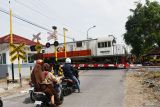 Sejumlah pengendara berhenti di dekat pintu perlitasan Jalur Perlintasan Langsung (JPL) 04 Ngetrep saat Kereta Api (KA) melintas di Kabupaten Madiun, Jawa Timur, Jumat (15/11/2024). Pemprov Jatim bersama Pemkab Madiun membangun pos jaga dan palang pintu KA di lokasi tersebut yang mulai dioperasionalkan Jumat (15/11) guna meningkatkan keselamatan masyarakat yang melewati perlintasan KA. Antara Jatim/Siswowidodo/mas.