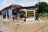 Sejumlah anak bermain di  jalan yang terendam banjir di depan kantor Kelurahan Kelun, Kota Madiun, Jawa Timur, Senin (18/11/2024). Sejumlah wilayah kelurahan dan desa di Kota dan Kabupaten Madiun terdampak banjir akibat hujan deras hingga sungai meluap yang menyebabkan sejumlah rumah, ruas jalan, sawah, dan dua gedung sekolah terendam sehingga murid diliburkan. Antara Jatim/Siswowidodo/um