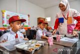 Petugas membagikan makanan gratis kepada siswa di SDN Sirahcai, Jatinangor, Kabupaten Sumedang, Jawa Barat, Senin (18/11/2024). Untuk mendukung Program Makan Bergizi Gratis yang direncanakan pemerintah pusat, Pemprov Jabar akan memanfaatkan bahan baku lokal yang dipasok dari 27 kabupaten/kota di wilayahnya. ANTARA FOTO/Raisan Al Farisi/agr
