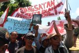 Sejumlah petani dari desa Satak membentangkan poster dan foto presiden saat unjuk rasa di depan Kantor Perum Perhutani, Kota Kediri Jawa Timur, Senin (18/11/2024). Aksi ratusan petani yang disertai dengan penutupan jalan tersebut guna menuntut kejelasan kepada Perhutani terkait hak garap lahan Hutan Produksi Daerah (HPD) Satak seluas 180 hektare.  ANTARA Jatim/Prasetia Fauzani/mas.