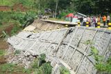 Petugas memeriksa kondisi bahu jalan yang amblas terseret longsor di jalur Selingkar Wilis, Desa Samar, Kecamatan Pagerwojo, Tulungagung, Jawa Timur, Kamis (21/11/2024). Konstruksi plengseng/talud sepanjang 50 meter dan ketinggian sekitar 11 meter ini ambrol akibat hujan deras yang mengguyur wilayah iu pada Rabu (2/11/2024) menyebabkan separuh badan jalan amblas sehingga arus lalu lintas diberlakukan sistem buka-tutup demi keselamatan. ANTARA Jatim/Destyan Sujarwoko/mas.