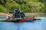 Pelajar dengan sepeda motornya menyeberangi kali Mantiung menggunakan perahu menuju sekolah di Desa Kutakarang, Pandeglang, Banten, Rabu (20/11/2024). Desa Kutakarang merupakan salah satu desa terisolir yang hanya dapat ditempuh dengan menyeberangi kali Mantiung menggunakan perahu dan tidak bisa dilintasi ketika air pasang. ANTARA FOTO/Muhammad Bagus Khoirunas/tom.