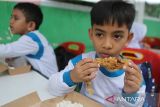 Sejumlah siswa menyantap  makan siang dengan menu ikan saat kegiatan makan bergizi gratis (MBG)  di Madrasyah Ibtidaiyah Negeri (MIN) 7, Banda Aceh, Aceh, Kamis (21/11/2024). Kegiatan makan bergizi gratis dengan menu ikan, daging, sayur dan buah di sekolah itu dalam rangka memperingati Hari Ikan Nasional  tahun 2024 dan  sekaligus  kampanye gemar makan ikan kepada siswa. ANTARA FOTO/Ampelsa.