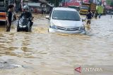 Pengendara motor dan mobil berusaha melintasi banjir di Dayeuhkolot, Kabupaten Bandung, Jawa Barat, Jumat (22/11/2024). BPBD Kabupaten Bandung mencatat sebanyak dua kecamatan di Kabupaten Bandung terdampak banjir setinggi 30cm hingga 110cm akibat meluapnya Sungai Citarum. ANTARA FOTO/Novrian Arbi/agr