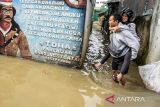 Warga menggendong pasanganya saat berjalan melintasi banjir di Dayeuhkolot, Kabupaten Bandung, Jawa Barat, Jumat (22/11/2024). BPBD Kabupaten Bandung mencatat sebanyak dua kecamatan di Kabupaten Bandung terdampak banjir setinggi 30cm hingga 110cm akibat meluapnya Sungai Citarum. ANTARA FOTO/Novrian Arbi/agr